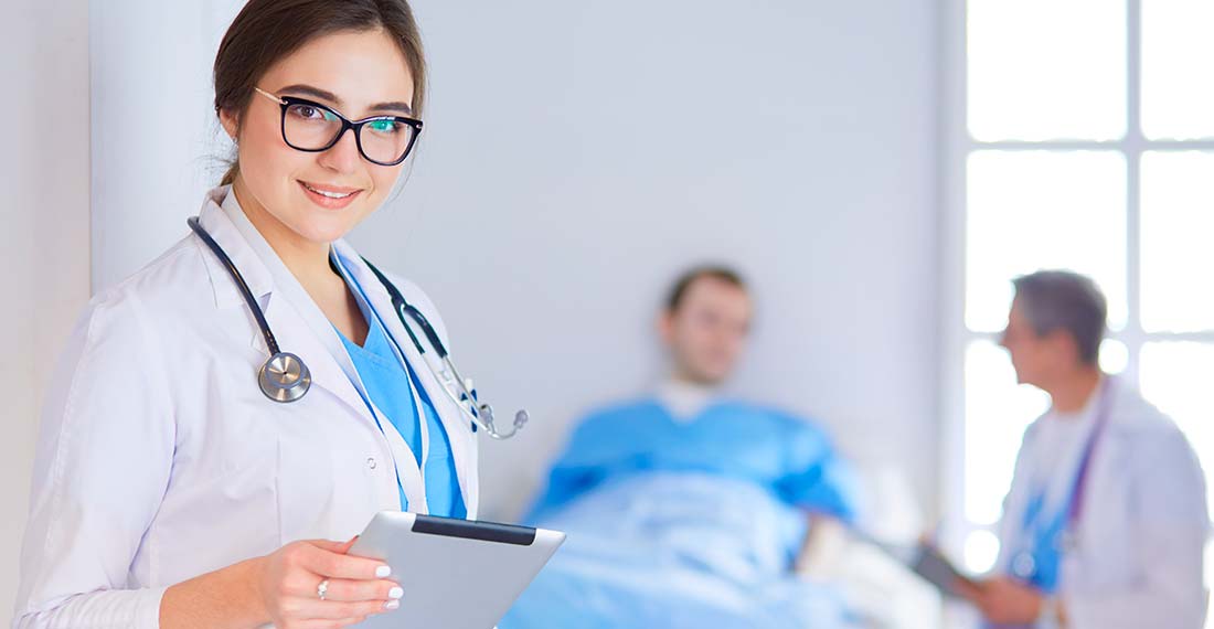женщина врач в очках на фоне пациента в больничной палате